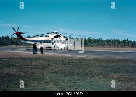 Un hélicoptère Sikorsky d'Ansett ANA au sol dans le Queensland, en Australie, en 1965. Il a été numéroté VH-BRI et nommé 'Golden Islander'. Il a été utilisé sur un service de passagers de Proserpine à Hayman Island qui a commencé en 1965. Ansett Australia a été fondée par Reginald «Reg» Ansett en 1935, alors qu'Ansett Airways Pty Ltd. En 1957 Ansett Airways a acheté Australian National Airways (ANA). À partir de 1981, il a été connu sous le nom d'Ansett et en 1990 est finalement devenu Ansett Australia. Cette image provient d'un ancien transparent couleur Kodak amateur, une photographie vintage des années 1960. Banque D'Images
