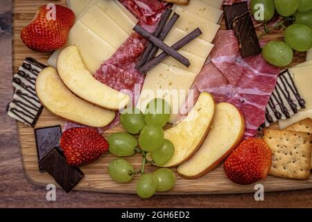 Gros plan de chocolat, de fromage, de craquelins et de fruits sur un tableau de charcuterie Banque D'Images