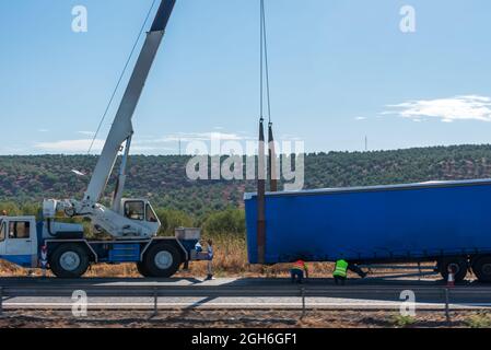 Grue soulevant une semi-remorque écrasée sur la route. Banque D'Images