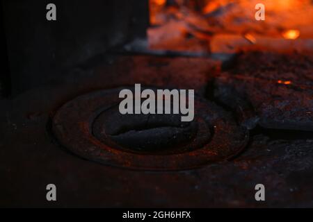 Foyer à bois. Gros plan de brûleur de fer antique. Bois de chauffage brûlant dans une vieille cuisinière ou un four. Noir et foncé. Flamme orange. Énergie thermique. Fer ouvert Banque D'Images