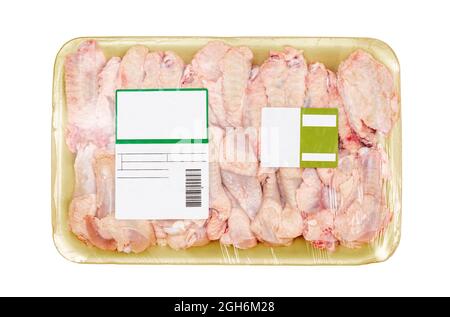 Ailes de poulet crues emballées dans une plaque en mousse de polystyrène avec une étiquette sur fond blanc. Banque D'Images