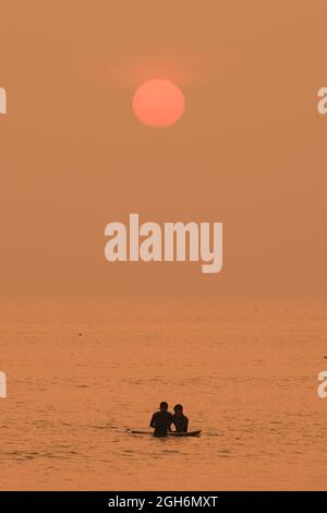 Gower, Swansea, Royaume-Uni. 5 septembre 2021. Météo au Royaume-Uni: Les surfeurs attendent avec espoir une vague sous le soleil couchant, lors d'une belle soirée balmy avec un soleil chaud et brumeux à la plage de Llangennith sur la péninsule de Gower. On prévoit que le sud du pays sera très bien au cours des deux prochains jours, mais on s'attend à des températures et des averses plus basses dans tout le pays plus tard dans la semaine. Credit: Gareth Llewelyn/Alamy Live News Banque D'Images