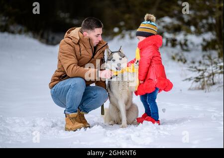 Père heureux et petite fille et chien husky en hiver randonnée en forêt en hiver.new Banque D'Images