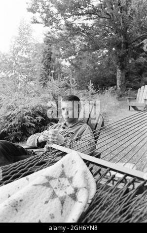 HOUGHTON, ÉTATS-UNIS - 27 juillet 2021 : photo verticale d'un jeune homme assis sur une chaise sur une terrasse et prenant du café le matin Banque D'Images