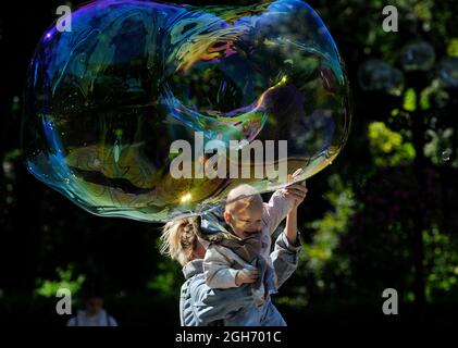 Kiev, Ukraine. Le 05septembre 2021. Une femme porte un enfant pour l'amener à toucher une énorme bulle de savon dans le parc. Crédit : SOPA Images Limited/Alamy Live News Banque D'Images