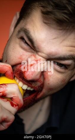 un gars mord un citron sur un fond rouge . portrait en gros plan Banque D'Images