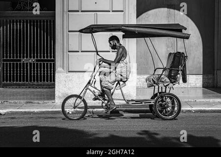 Un homme sur son vélo sur le chemin de trouver de nouveaux clients avec son taxi dans la vieille havanna, cuba Banque D'Images