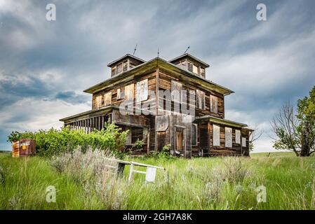 Une ancienne maison abandonnée dans les Prairies de la Saskatchewan avec un berceau au premier plan Banque D'Images