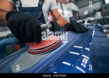 Réparateur équipé d'une ponceuse qui retire la vieille peinture de la voiture Banque D'Images