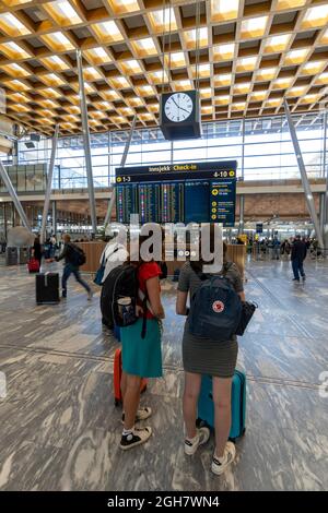 Deux jeunes femmes qui regardent le tableau horaire de l'aéroport d'Oslo Gardermoen à Oslo, Norvège, Europe Banque D'Images