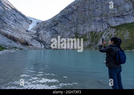 Touriste prenant des photos avec son smartphone au glacier Briskdal, parc national du glacier Jostedal, Norvège, Europe Banque D'Images