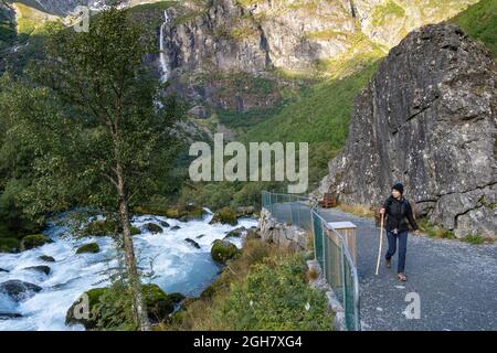 Jeune femme marchant avec un bâton au glacier Briskdal, parc national du glacier Jostedal, Norvège, Europe Banque D'Images