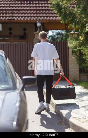 Messenger en uniforme noir avec le sac thermo court sur pied vraiment rapide pour livrer rapidement des pizzas chaudes juste au four Banque D'Images