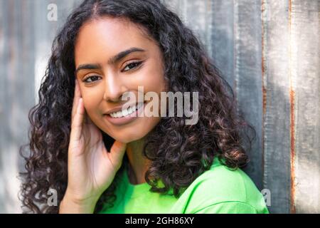 Portrait extérieur de la belle course mixte heureuse africaine fille américaine adolescente jeune femme pensant et souriant avec des dents parfaites dans un c urbain Banque D'Images