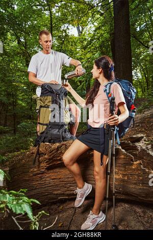 Un couple joyeux qui boit du thé pendant la marche nordique Banque D'Images