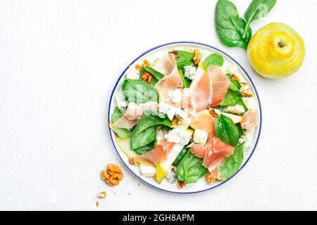 Salade de poires au prosciutto, fromage bleu, épinards, noix sur fond blanc, vue de dessus, espace copie Banque D'Images
