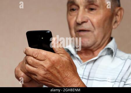 Homme âgé utilisant un téléphone portable, regardant surpris sur l'écran de smartphone. Concept de la communication en ligne dans la retraite, la victoire, les sms, la lecture des nouvelles Banque D'Images