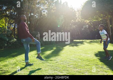 Père afro-américain avec son fils s'amusant et jouant au football dans le jardin Banque D'Images