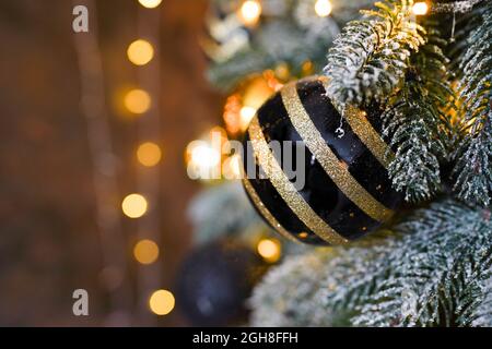 Décoration de Noël dorée et noire suspendue sur l'arbre avec un arrière-plan flou Banque D'Images