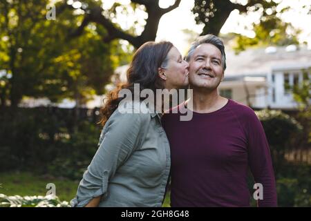 Joyeux couple caucasien âgé embrassant et souriant dans le jardin Banque D'Images