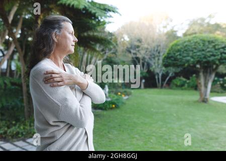 Femme caucasienne senior attentionnés avec les armes croisées dans le jardin Banque D'Images