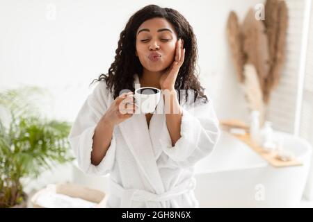 Black Lady tenant une tasse de café faisant le visage de canard dans la salle de bains Banque D'Images