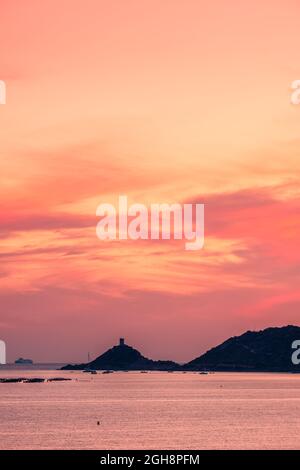 Un ferry passe devant la tour génoise de la Pointe de Parata dans les îles Sanguinaires près d'Ajaccio en Corse au coucher du soleil Banque D'Images