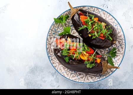 Aubergine farcie cuite avec différents légumes, tomate, poivre, oignon et persil sur fond de table en pierre grise ou en béton. Vue de dessus Banque D'Images