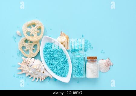 Sel de mer, crème, éponges et coquilles dans un ensemble de cosmétiques pour le spa sur fond bleu. Vue de dessus avec espace pour le texte Banque D'Images