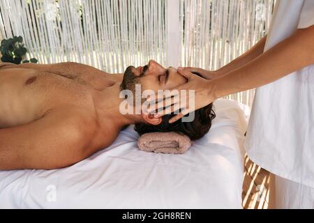 Le beau homme reçoit un massage de la tête et se détend au spa. Massage de la tête anti-stress, gros plan Banque D'Images