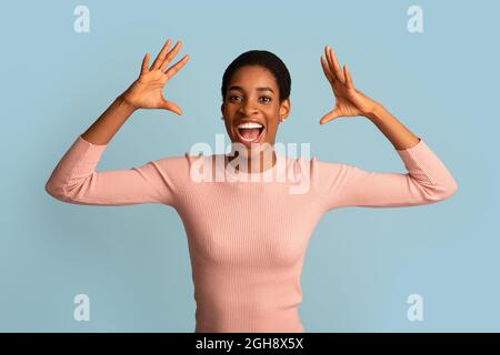 Grande chance. Une femme noire euphorie excitée criant avec joie et levant les mains Banque D'Images