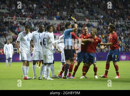 L'arbitre Juan Soto, Iker muniain (2e R) d'Espagne, reçoit une carte jaune pour avoir affronté José Mendoza (pas dans le pic) du Honduras lors du premier match des Jeux Olympiques de Londres 2012, le groupe D, entre l'Espagne et le Honduras, au parc St. James, Newcastle upon Tyne le 29 juillet 2012. Banque D'Images