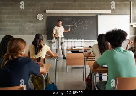 De retour à l'école, l'enseignant enseigne les élèves en classe. L'éducation dans l'école secondaire. Banque D'Images