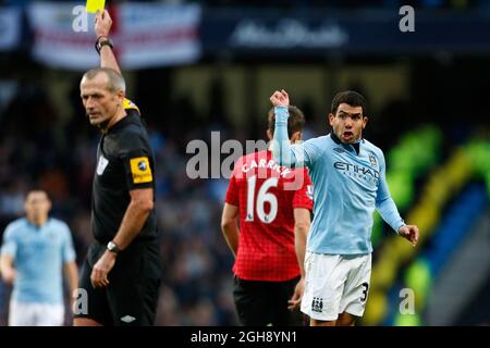 Carlos Tevez (R) de Manchester City se présente à l'arbitre Martin Atkinson après avoir reçu une carte jaune lors du match de la Barclays Premier League entre Manchester City et Manchester United au Etihad Stadium de Manchester, en Angleterre, le 9 décembre 2012. Banque D'Images