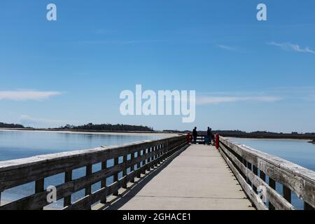 Les hommes pêchant au bout d'une longue promenade sur la jetée sur la voie navigable intracôtière, magnifique ciel bleu reflété dans l'eau, aspect horizontal Banque D'Images