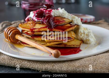 Petit-déjeuner pour les athlètes avec crêpes à l'épeautre recouvertes de fromage cottage, de cerises et de miel Banque D'Images