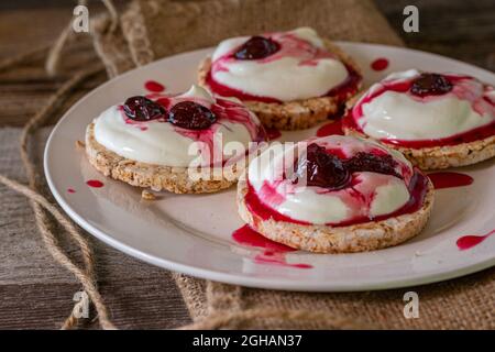 En-cas naturel sucré et sain avec gâteau de riz brun recouvert de skyr ou Quark et confiture de cerises acides russe maison appelée warenje servi sur une assiette Banque D'Images