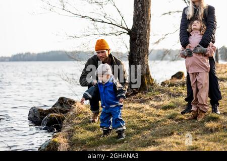 Homme et femme avec fils et fille au bord du lac au parc Banque D'Images