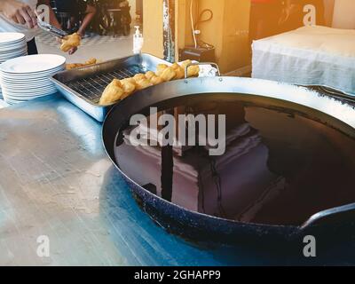 Bâtonnets de pâte ou pâte chinoise frite appelée patongo à vendre sur plateau près d'une grande poêle à frire. Patongo est un bâton de pâte frite. Célèbre traditiona Banque D'Images