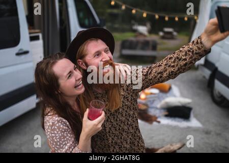 Des amis hommes et femmes heureux prenant le selfie sur un smartphone pendant le camping Banque D'Images