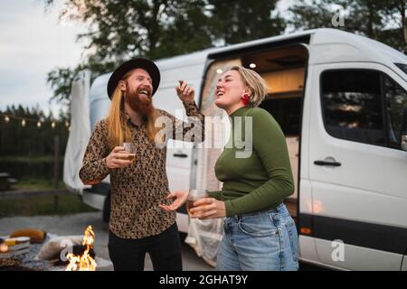 Un jeune couple heureux dansant en camping-car le soir Banque D'Images
