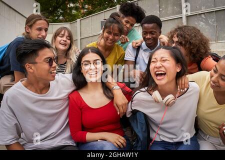 Une fille entourée de camarades de classe regardant un appareil photo souriant. Des élèves heureux à l'école secondaire. Banque D'Images