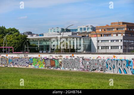 Berlin, Allemagne - 30 juillet 2021 : mur de Berlin (allemand : Berliner Mauer) avec des graffities, côté est, et la gare Ostbahnhof de Berlin à l'arrière-plan Banque D'Images
