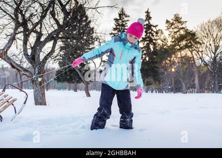 Teengae fille s'amusant à jouer avec le traîneau dans la neige en hiver. Banque D'Images