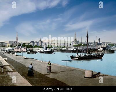 Vue du début du XXe siècle sur le port de Dún Laoghaire, une ville côtière de banlieue du comté traditionnel de Dublin en Irlande. La ville a été construite conformément à la législation de 1816 qui a permis la construction d'un grand port pour desservir Dublin. Il était connu sous le nom de Dún Laoghaire jusqu'à ce qu'il soit rebaptisé Kingstown en l'honneur de la visite du roi George IV en 1821, et en 1920 il a reçu son nom actuel. Au fil du temps, la ville est devenue un quartier résidentiel, une station balnéaire et le terminus du premier chemin de fer d'Irlande. Banque D'Images