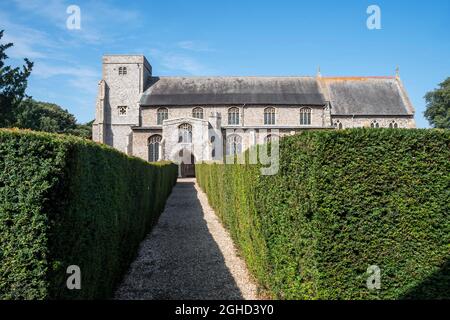 La longue avenue de haies de yew menant à l'église All Saints à Thornham sur la côte nord de Norfolk. Banque D'Images