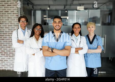 Équipe médicale internationale posant à la clinique tout en ayant l'esprit d'équipe Banque D'Images