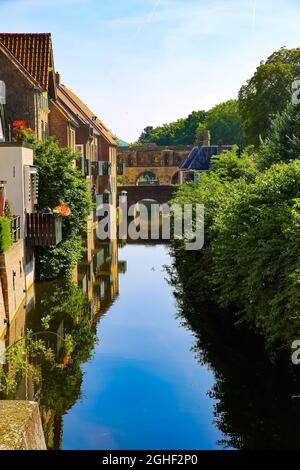 Vue sur le canal d'eau avec maisons et arbres mur médiéval en pierre watergate du XIVe siècle avec reflet contre ciel bleu d'été - Zutphen (Berk Banque D'Images