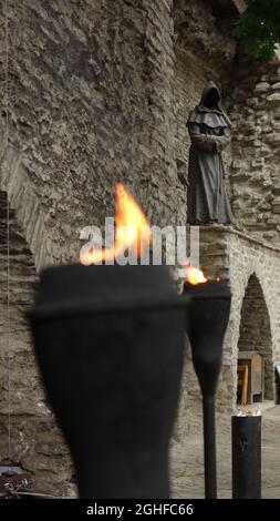 Une torche éclairée devant un bâtiment gothique médiéval sous la supervision d'une statue d'un moine, Tallinn, Estonie Banque D'Images