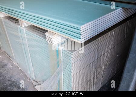 Feuilles de cloisons sèches dans une pile dans un entrepôt de matériaux de construction. Plaques de plâtre en stock Banque D'Images